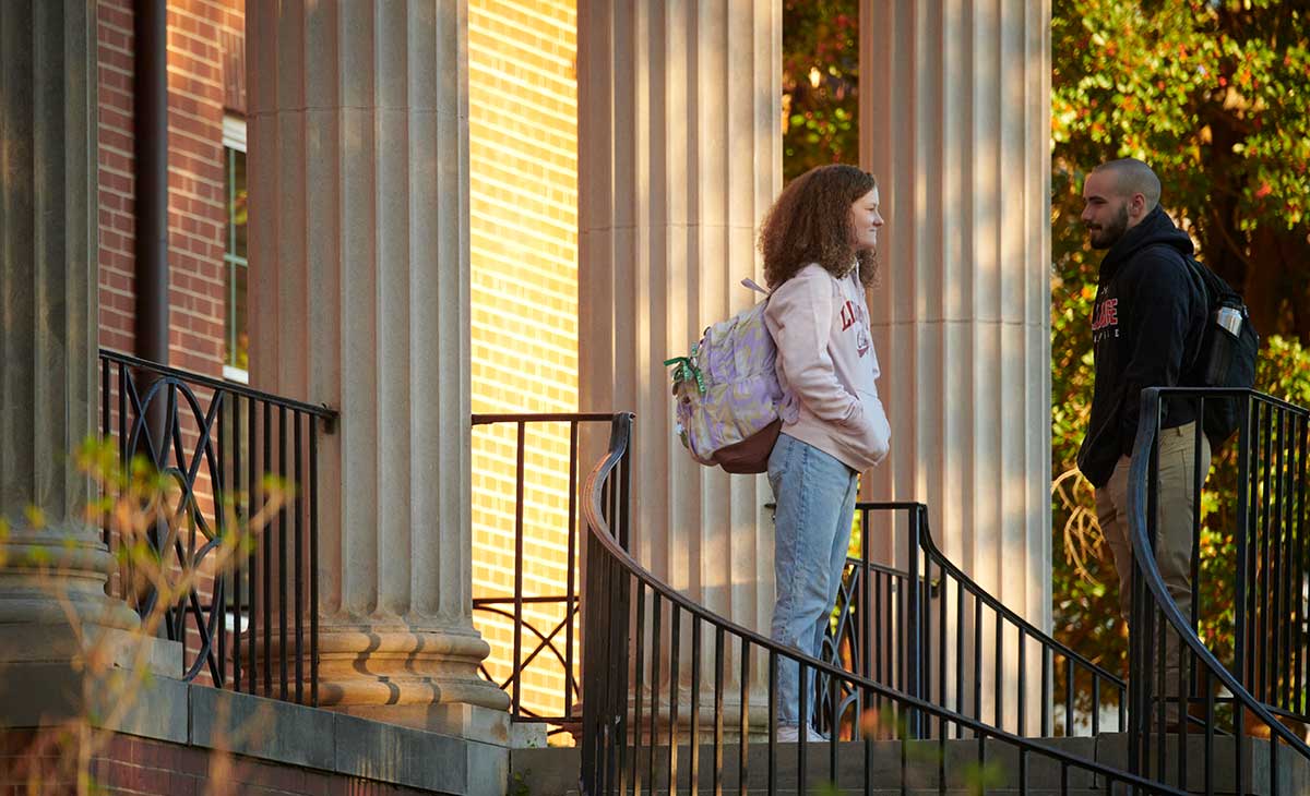 two students talk on a porch