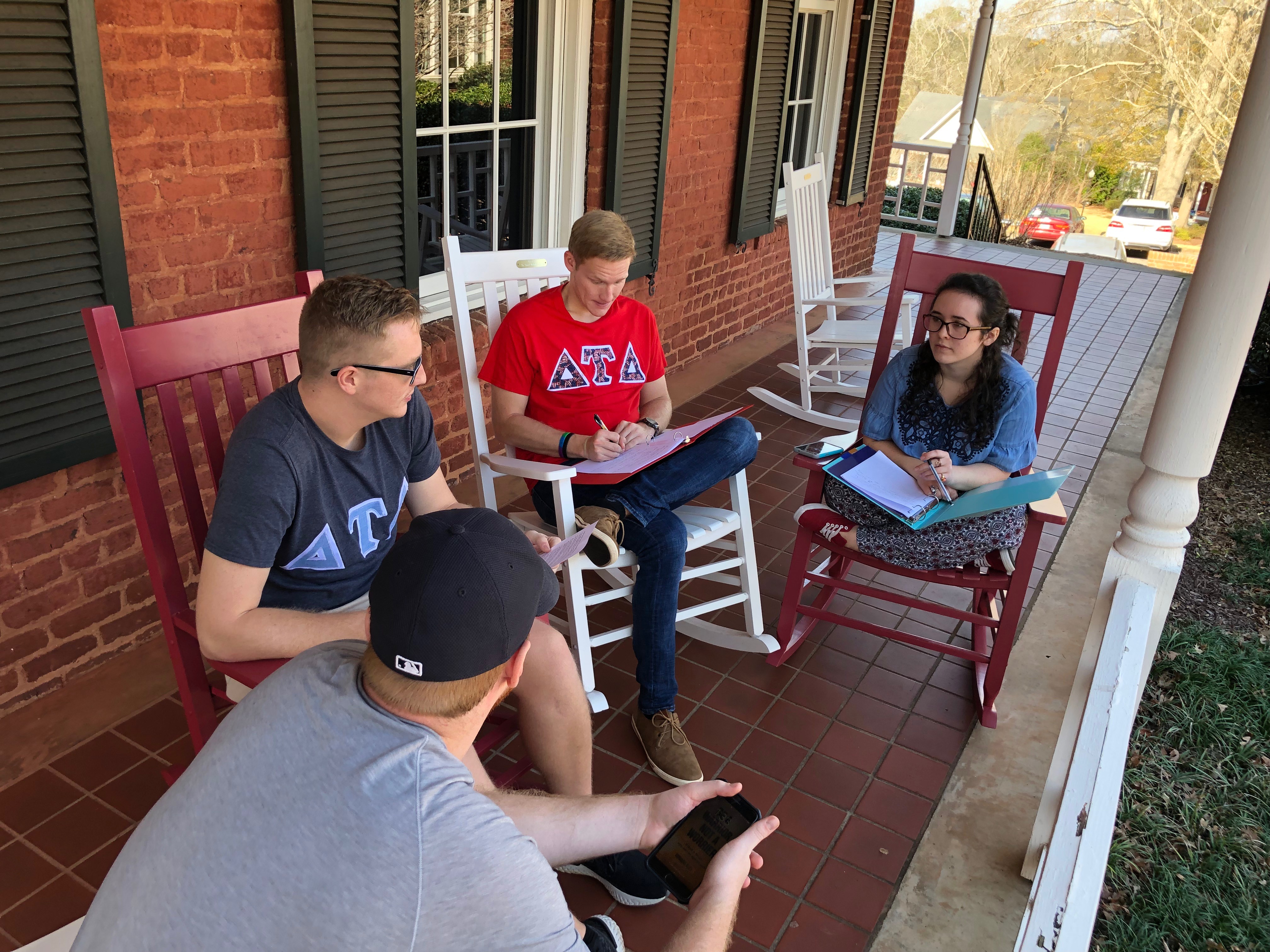 Three students sit on a swing at Smith Hall