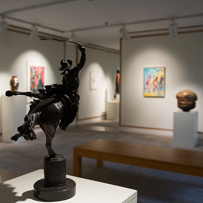 Sculpture in foreground and paintings on the wall in Art Center gallery.