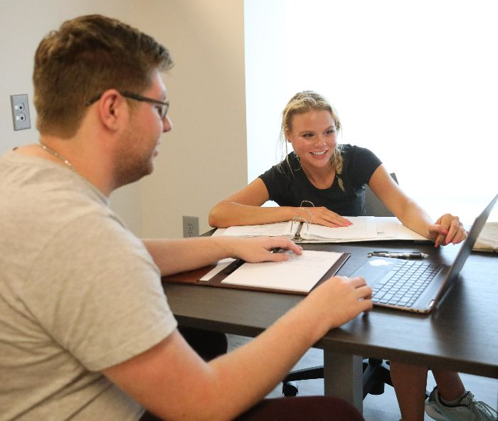 Male and Female student review a document on a laptop